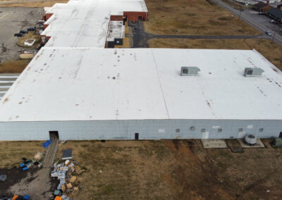 Aerial view showcasing a large industrial building surrounded by open space and infrastructure.
